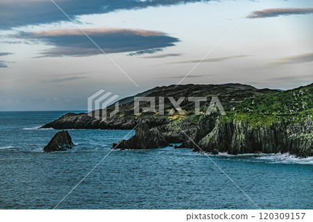 A view of a rocky coastline with a blue ocean. The water has a deep blue colour. The sky is clear and blue. The rocks are rugged and weathered. A view of a rocky coastline with a blue ocean. The water has a deep blue colour. The sky is clear and blue. The rocks are rugged and weathered. 120309157