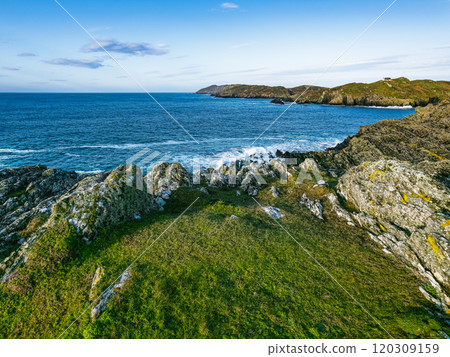 The serene coastline features rugged cliffs and rolling waves, with lush greenery in the foreground, capturing the beauty of nature on a sunny day. The serene coastline features rugged cliffs and rolling waves, with lush greenery in the foreground, capturing the beauty of nature on a sunny day. 120309159