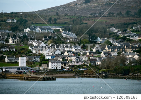 A picturesque scene of a small town nestled amidst a lush green hillside. The houses are mostly white and have black roofs, and there are trees and shrubs surrounding the area. A picturesque scene of a small town nestled amidst a lush green hillside. The houses are mostly white and have black roofs, and there are trees and shrubs surrounding the area. 120309163