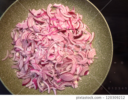 Chopped red onions sizzling in a frying pan on a stovetop during meal preparation 120309212