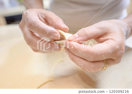 Making traditional dumplings with meat filling by hand in a cozy kitchen during a sunny afternoon Making traditional dumplings with meat filling by hand in a cozy kitchen during a sunny afternoon 120309216