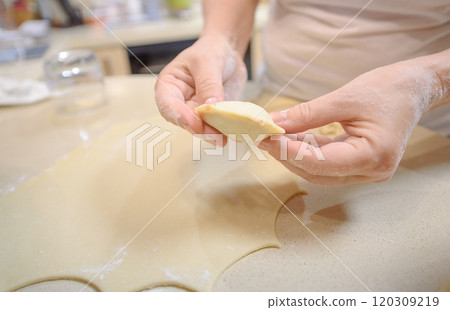 Person preparing handmade dumplings in a cozy kitchen during the afternoon Person preparing handmade dumplings in a cozy kitchen during the afternoon 120309219