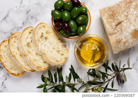 appetizer, sliced ciabatta bread, with olive oil, green olives, Chalkidiki olives, classic Green green olive, on a marble table, top view, no people, appetizer, sliced ciabatta bread, with olive oil, green olives, Chalkidiki olives, classic Green green olive, on a marble table, top view, no people, 120309387