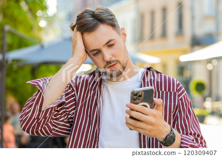 Surprised handsome man use smartphone loses, bad news, fortune loss fail outdoors in city street Surprised handsome man use smartphone loses, bad news, fortune loss fail outdoors in city street 120309407