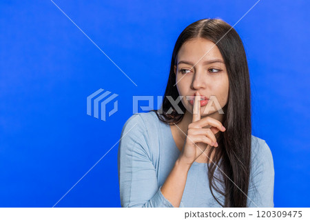 Young woman presses finger to lips makes silence gesture sign do not tells secret, stop gossip 120309475