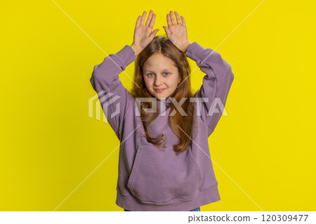 Smiling child girl doing bunny ears gesture on head, having fun, fooling with humorous comical mood Smiling child girl doing bunny ears gesture on head, having fun, fooling with humorous comical mood 120309477