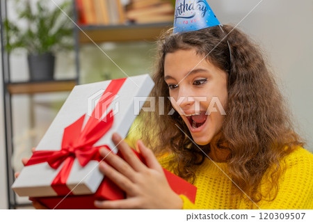Happy child girl kid hold birthday gift box with ribbon, celebrating party, opening present at home 120309507