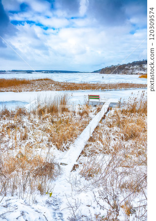Winter landscape by a frozen pond  in the evening. 120309574