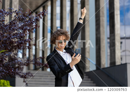 Businessman using smartphone celebrating win good message news lottery victory in downtown city 120309763