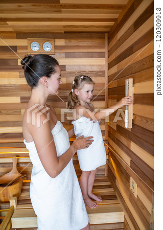 Mom and daughter control the time spent in the sauna enjoying time together. Girly pastime  120309918