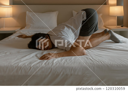 Man resting on the hotel bed as he tired from traveling. 120310059