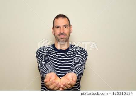 Portrait of a handsome, friendly bearded man offering something in his hands with arms outstretched. Studio shot isolated on beige background Portrait of a handsome, friendly bearded man offering something in his hands with arms outstretched. Studio shot isolated on beige background 120310134