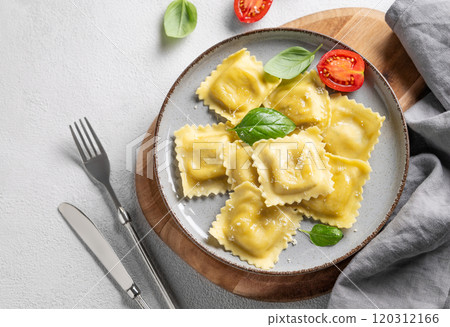 Homemade ravioli pasta with cheese, tomatoes and basil in a plate on a wooden board Homemade ravioli pasta with cheese, tomatoes and basil in a plate on a wooden board 120312166