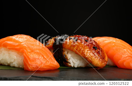 Delicious sushi pieces with salmon, eel and rice on black background Delicious sushi pieces with salmon, eel and rice on black background 120312522