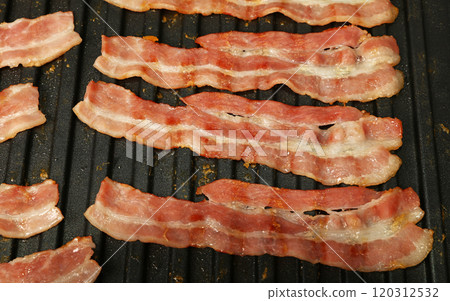 Close up cooking bacon slices on electric grill 120312532