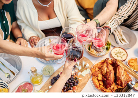 Top view group of adult friends clinking wine glasses and enjoying drinks over dinner table celebrating holidays together copy space Top view group of adult friends clinking wine glasses and enjoying drinks over dinner table celebrating holidays together copy space 120312847