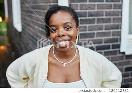 Portrait of cheerful adult African American woman looking at camera with smile while posing outdoors wearing comfy casual sweater 120312881