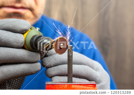 skilled male mechanic using a handheld engraving drill to precisely cut and process metal skilled male mechanic using a handheld engraving drill to precisely cut and process metal 120313289