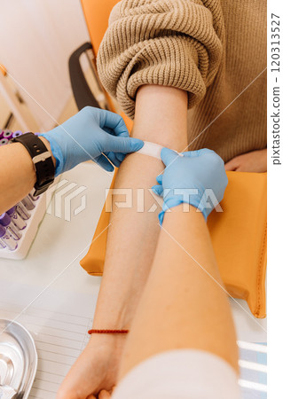 Healthcare professional applying a bandage after a blood draw procedure in a clinical setting Healthcare professional applying a bandage after a blood draw procedure in a clinical setting 120313527