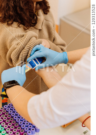 Phlebotomist applying a tourniquet to patient's arm during blood draw in a medical laboratory. Phlebotomist applying a tourniquet to patient's arm during blood draw in a medical laboratory. 120313528