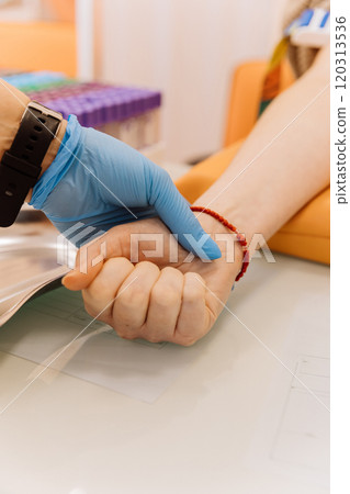 Medical professional holding patient's wrist during blood collection procedure in a clinic setting Medical professional holding patient's wrist during blood collection procedure in a clinic setting 120313536