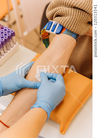 Healthcare professional applying cotton on patient's arm after blood collection in a medical clinic Healthcare professional applying cotton on patient's arm after blood collection in a medical clinic 120313541