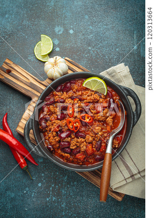 Mexican dish Chili con carne with lime, garlic and chili pepper on dark background top view 120313664