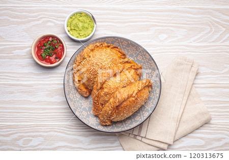 Delicious baked empanadas with sesame seeds in a bowl with sauces, traditional Spanish savoury pastry Delicious baked empanadas with sesame seeds in a bowl with sauces, traditional Spanish savoury pastry 120313675