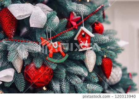 Close up of red decorations on artificial green Christmas tree with snow. 120313940