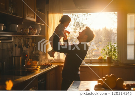 Father lifting laughing child in sunny kitchen while cooking 120314145