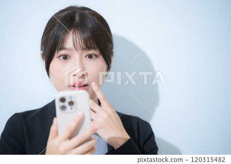一位穿著西裝、看著智慧型手機的驚訝女人的特寫商業場景 120315482