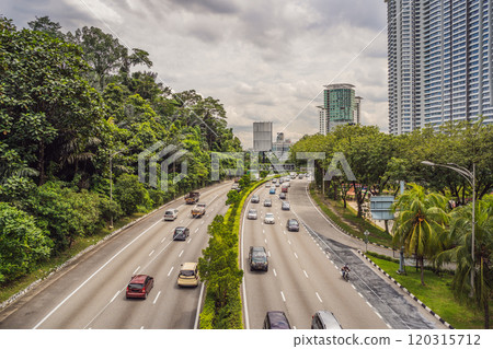 Highway with cars surrounded by greenery and skyscrapers 120315712