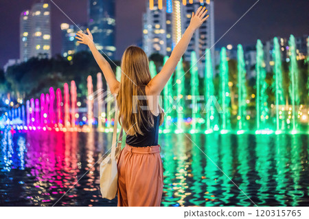 Woman tourist on background of colorful fountain on the lake at night, near by Twin Towers with city on background. Kuala Lumpur, Malaysia 120315765