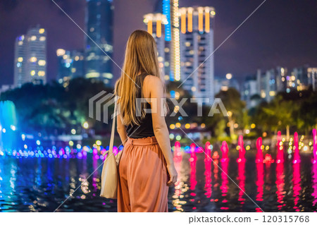 Woman tourist on background of colorful fountain on the lake at night, near by Twin Towers with city on background. Kuala Lumpur, Malaysia 120315768