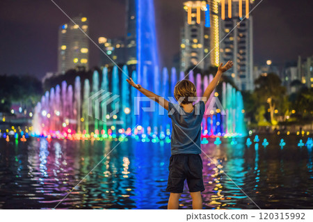 Boy on background of colorful fountain on the lake at night, near by Twin Towers with city on background. Kuala Lumpur, Malaysia 120315992