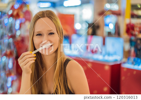A woman with paper strips in her hands listens to the fragrance in the mall 120316013