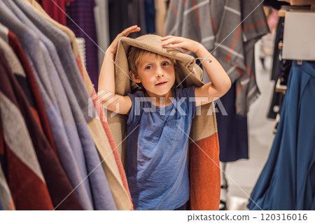 The boy tries on clothes in the childrens clothing store 120316016