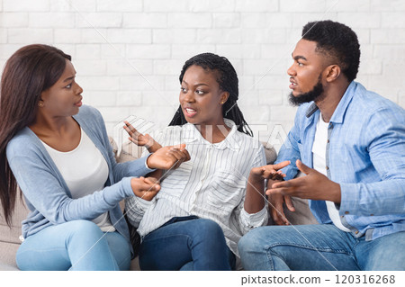Upset black woman trying to stop friends from quarreling, sitting between them and actively gesturing, copy space 120316268