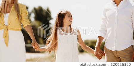 Leisure with family. Parents and child walking, holding hands and spending time in countryside Leisure with family. Parents and child walking, holding hands and spending time in countryside 120316390