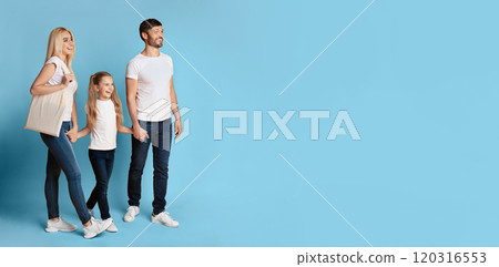 A young family walks together, holding hands, against a bright blue background, looking at copy space, panorama 120316553