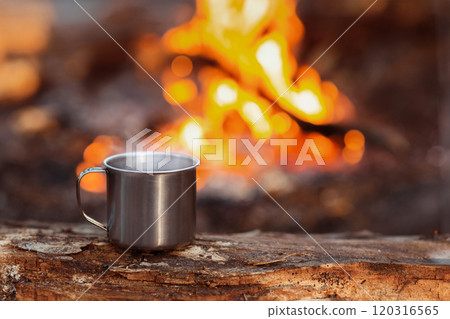 Camping titanium cup on wood over fire background. Lunch during journey to the wild. Camping lifestyle, copy space 120316565