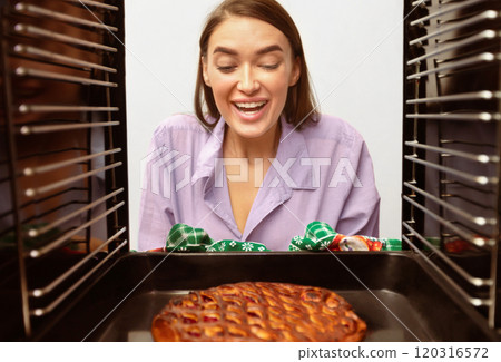 Great baking. Happy girl removing handmade pie from oven, view from inside 120316572