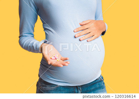 Medications and pregnancy. Expectant woman holding pills and touching belly, white background 120316614
