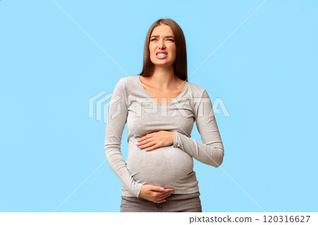 Pregnant Woman Suffering From Pain Touching Belly Standing Over Gray Studio Background. Empty Space 120316627