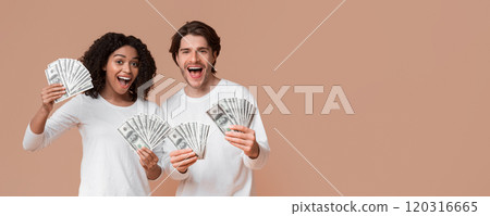 Lucky winners. Happy guy and afro girl holding lot of dollar cash in hands, rejoicing success together, posing over yellow background, copy space 120316665