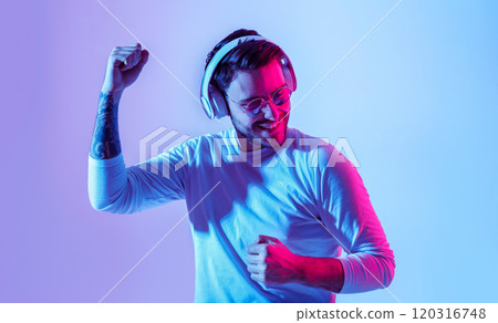 Dancing to favorite music. Fashionable guy with headphones has fun with favorite song, studio shot 120316748