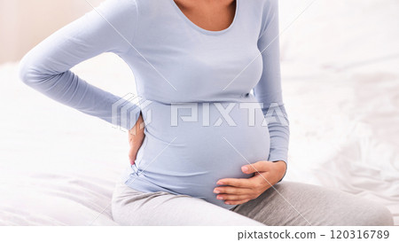 Unrecognizable Pregnant Woman Having Backache Touching Back And Belly Sitting In Bed At Home. 120316789