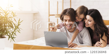 Lazy Family Weekend. Happy Parents And Cute Little Daughter Using Laptop In Bed, Downloading Movies To Watch, Browsing Internet 120316848