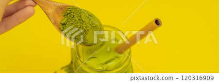 Green tea latte with ice in mason jar and straw and spoon with powder matcha on yellow background. Homemade Iced Matcha Latte Tea with Milk zero waste BANNER, LONG FORMAT 120316909