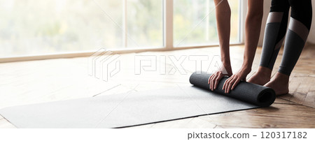 Cropped photo of girl getting ready before morning yoga practice, placing her yoga mat on floor at fitness studio, panorama with copy space 120317182